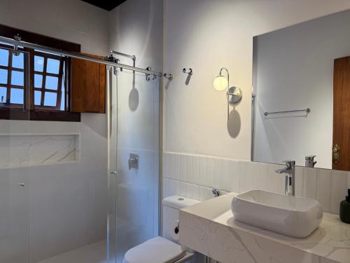 a bathroom with a sink and a shower and a toilet at Casa Matutina Colonial-Conforto Moderno no Centro Histórico in Pirenópolis