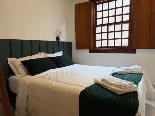 a bedroom with a large bed with a green headboard at Casa Matutina Colonial-Conforto Moderno no Centro Histórico in Pirenópolis