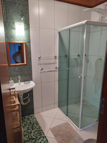 Un baño con ducha de cristal y lavabo. en Solar Grace casa 02, en Bombinhas