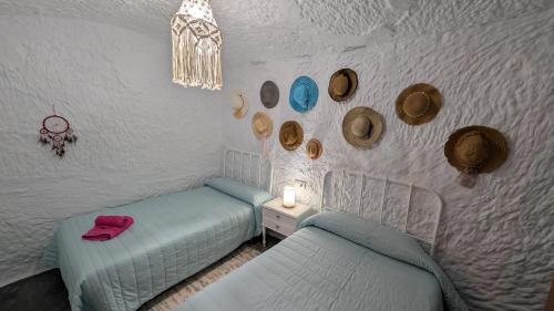 a bedroom with two beds and a table with a lamp at Cueva Rincón Bustamante in Gorafe