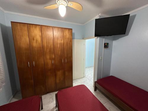 a bedroom with a wooden cabinet and a red bed at Casa no Centro de Bertioga com Piscina in Bertioga