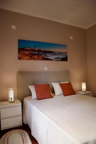 a bedroom with two beds and two lamps and a painting at Faria's House 2 in Feiteiras