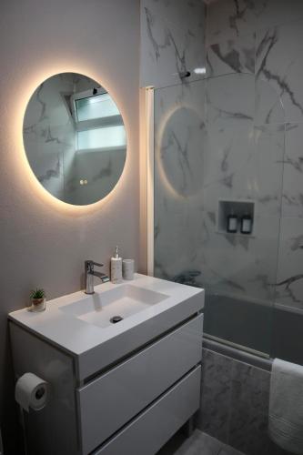 a white bathroom with a sink and a mirror at Faria's House 2 in Feiteiras
