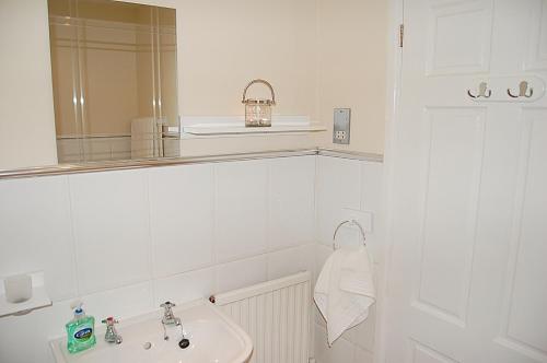 a white bathroom with a sink and a mirror at Saint Cadfans Lodge in Tywyn