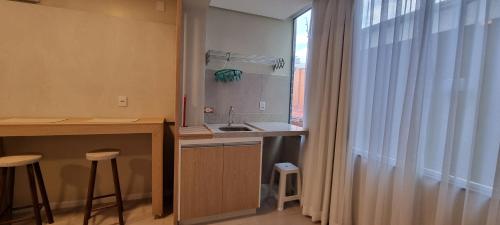 eine Küche mit Spüle und Theke mit Fenster in der Unterkunft Jk LOFT à beira-mar de CAPÃO DA CANOA, com ar condicionado split in Capão da Canoa