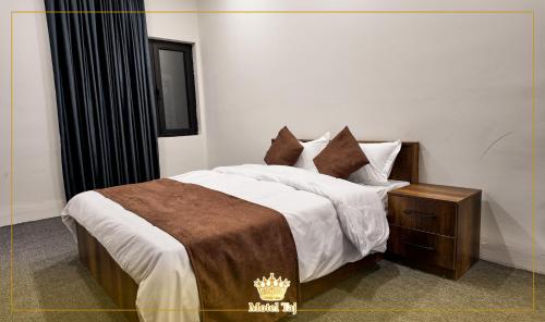 a bedroom with a king sized bed with a brown blanket at Motel Taj in As Sulaymānīyah
