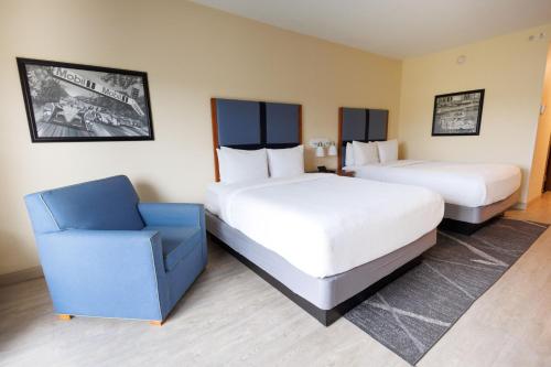 a hotel room with two beds and a chair at SEVEN Sebring Raceway Hotel in Sebring