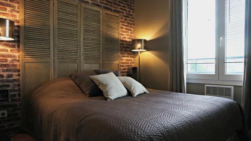 ein Schlafzimmer mit einem Bett mit zwei Kissen und einer Ziegelwand in der Unterkunft Little Suite - Westhoek in Lille