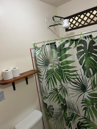 a bathroom with a shower curtain with palm leaves at Miss Miriam BeachFront Cabins in Tortuguero