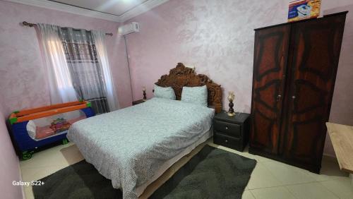 a bedroom with a bed and a wooden dresser at Appartement B à 7min de l’aéroport de Marrakech in Marrakech