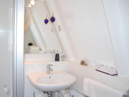Un baño blanco con lavabo y espejo. en Holiday home NurMeer, en Ahrenshoop