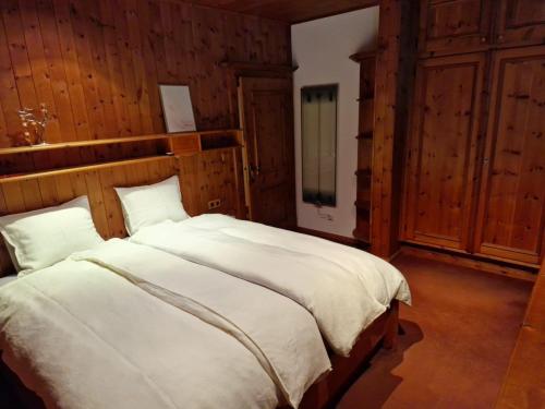a bedroom with a large white bed with wooden walls at Amazing cottage in Tyrol with sauna in Volders