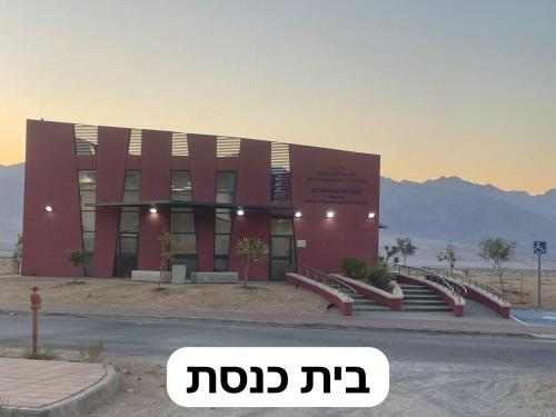 Beʼer Oraשלווה במדבר的一座红色的大建筑,前面有楼梯