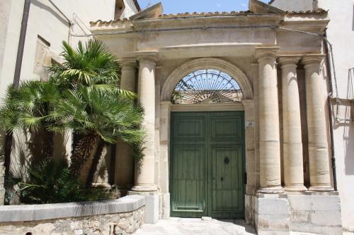 a building with a green door and a palm tree at La Chiave di Volta in Ragusa
