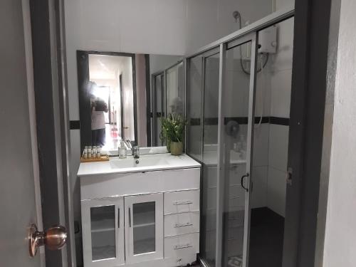 une salle de bains avec un lavabo blanc et une douche dans l'établissement KKs room 1, à Nadi