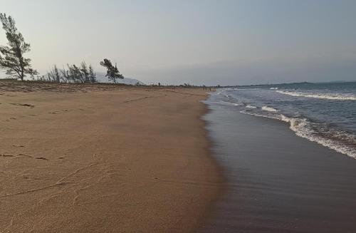 a sandy beach with trees and the ocean at Casa de praia Região dos Lagos - Unamar - Cabo Frio RJ in Cabo Frio