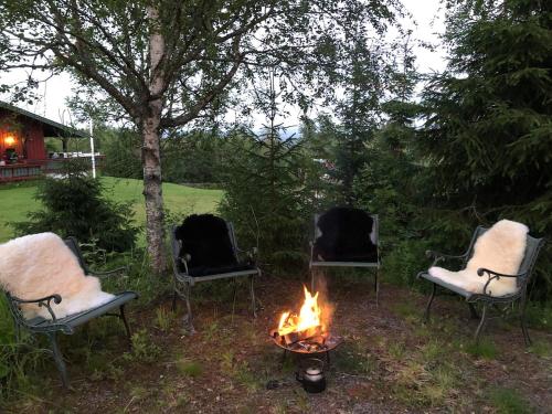 three chairs sitting around a fire in a yard at Cozy cabin 1,5 hours from Oslo in Hamar
