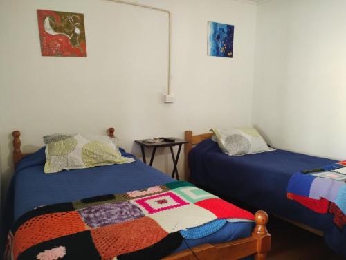 a bedroom with two beds and a table at Hostal Mirenart in Valparaíso