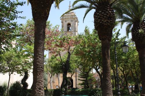 a building with a clock tower behind a bunch of trees at La Chiave di Volta in Ragusa
