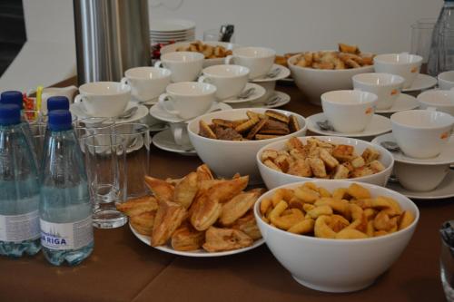 a table with bowls and plates of food and bottles of water at Oškrogs in Ķegums