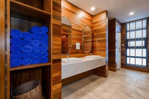 a bathroom with wooden walls and two sinks and a mirror at JD Luxury Lavanya Apartment in Pulau Tepur