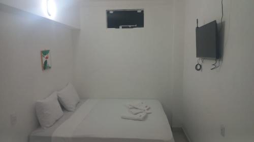 a bedroom with a white bed and a tv at iG Pousada - Frente Mar in Florianópolis