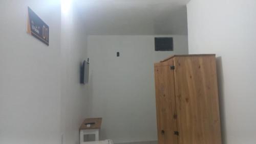 a room with a white wall and a wooden cabinet at iG Pousada - Frente Mar in Florianópolis
