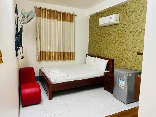 a small bedroom with a bed and a red chair at Huynh Mai Hostel in Can Tho