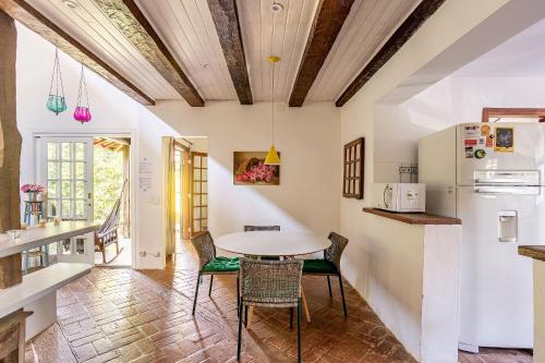 a kitchen and dining room with a table and chairs at Casa dos Pássaros na areia a 20m da Praia da Baleia com 3 suítes e 1 dorm com ar condicionado, wifi, smart tv, cozinha completa e churrasqueira in Barra do Sahy