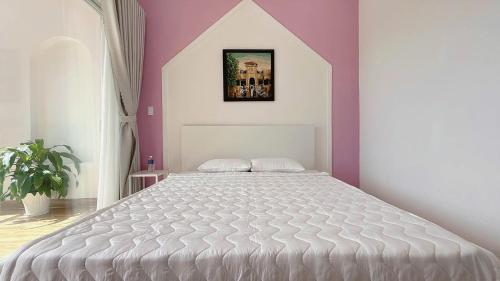a bedroom with a large white bed with purple walls at Homestay NAD nguyên căn tại Phan Thiết in Ấp Sung Xuân