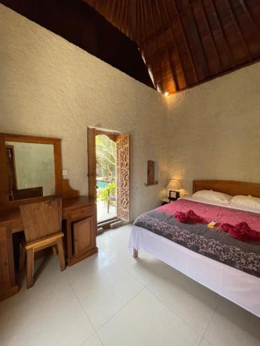 a bedroom with a bed and a desk and a mirror at Satria Bungalow in Uluwatu