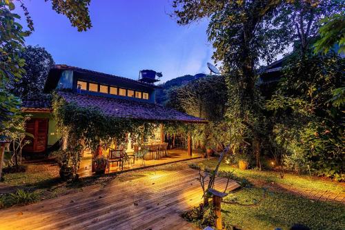 a house with a wooden deck in the yard at Casa dos Pássaros na areia a 20m da Praia da Baleia com 3 suítes e 1 dorm com ar condicionado, wifi, smart tv, cozinha completa e churrasqueira in São Sebastião