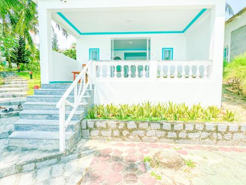 a white house with stairs and a porch at Paradise Resort Doc Let - All Inclusive in Doc Let