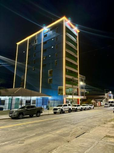 a large building with cars parked in a parking lot at Swamy Hotel in Cruzeiro do Sul