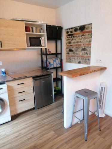 une cuisine avec un comptoir et un tabouret dans une pièce dans l'établissement Studio centre ville st aubin, à Toulouse