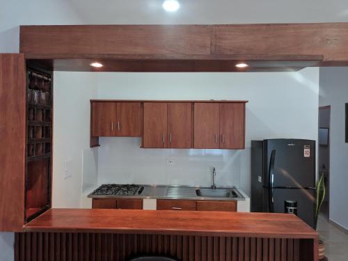 a kitchen with wooden cabinets and a black refrigerator at Apartamento Confort - Planta Alta in Arboletes
