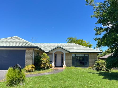 a house with a green lawn in front of it at Family Retreat with Playground Views in East Tamaki in Auckland