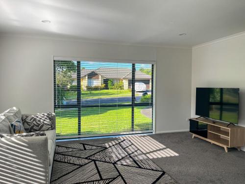 a living room with a couch and a large window at Family Retreat with Playground Views in East Tamaki in Auckland