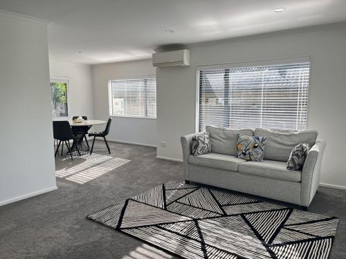 a living room with a couch and a table at Family Retreat with Playground Views in East Tamaki in Auckland