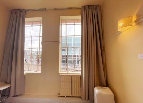 a bathroom with a window with curtains and a toilet at Grand Central Serviced Apartments in Auckland