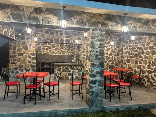 un ristorante con tavoli e sedie rossi di fronte a un muro di pietra di Rancho MM a Temixco