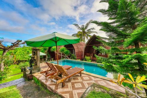 a swimming pool with two chairs and an umbrella at DNR Lumbung Garden in Nusa Penida