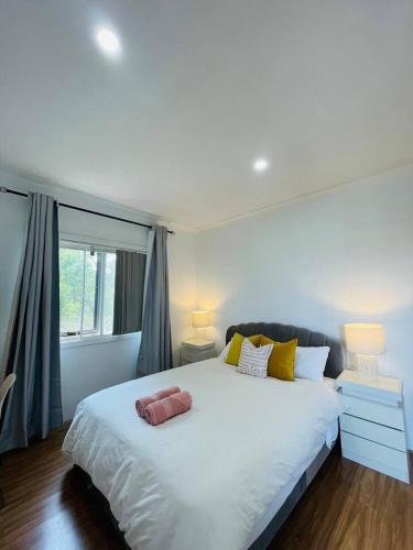 a large white bed in a room with a window at Lovely Modern Family home for your family and friends in Narwee