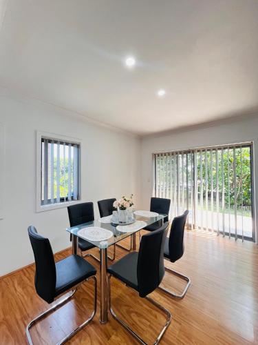 a dining room with a table and black chairs at Lovely Modern Family home for your family and friends in Narwee