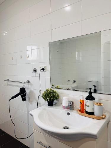 a white bathroom with a sink and a mirror at Lovely Modern Family home for your family and friends in Narwee