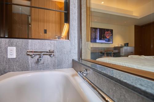 a bathroom with a sink and a mirror and a bed at Hotel Collective in Naha