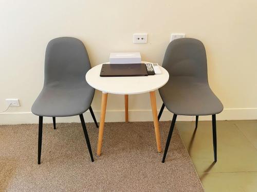 two chairs and a table with a laptop on it at Grand Central Serviced Apartments in Auckland