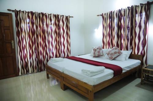 1 dormitorio con 1 cama con cortinas rojas y blancas en Luxury pool villa kovalam, en Trivandrum