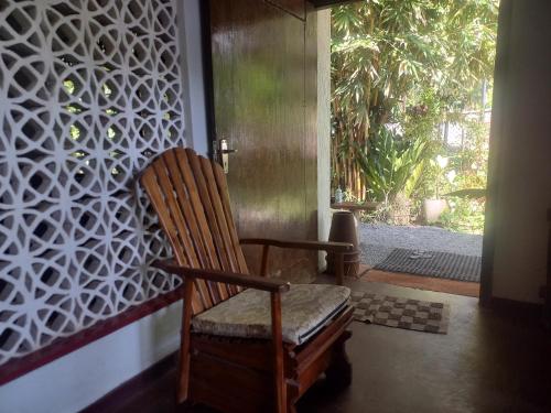 a wooden rocking chair sitting in front of a door at Oops in Unawatuna