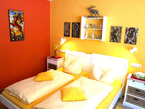 two beds in a room with orange and yellow at Haus am Kurpark in Schömberg